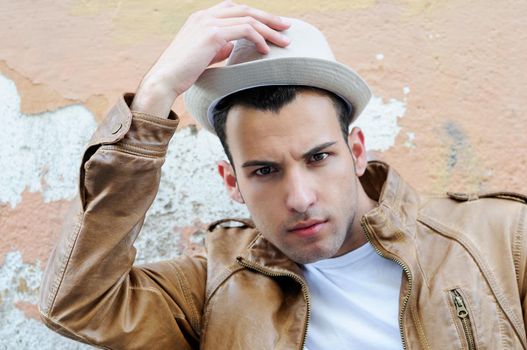 Portrait of a handsome young man with a hat in urban background