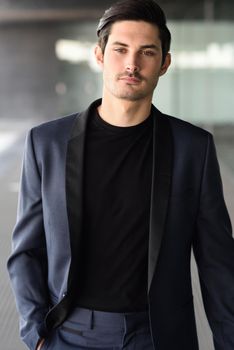 Portrait of an attractive young businessman outdoors, wearing modern suit.