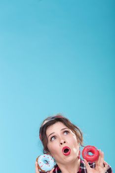 Junk food, diet and unhealthy lifestyle concept - pin-up woman with doughnuts over the blue background.