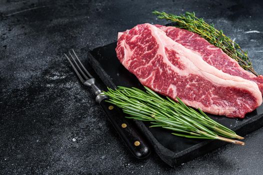 Raw Striploin steak or New York steak beef meat cut. Black background. Top view. Copy space.