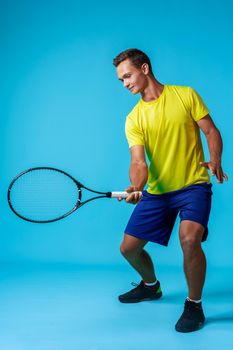 Full length studio portrait of a tennis player man on blue background close up