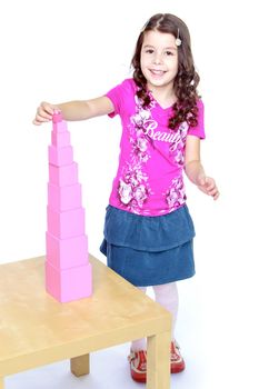 pink girl builds a tower in the school of Maria Montessori.Isolated on white background portrait.
