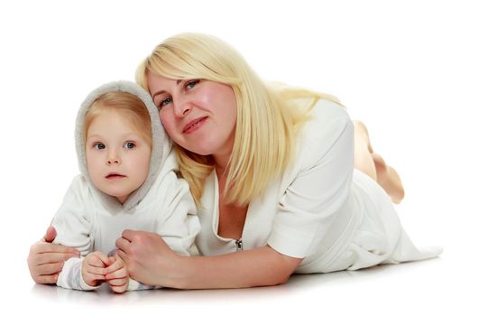 Happy family mother and little daughter lying on the floor and laughing directly into the camera.Isolated on white background.