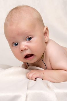 A charming baby lies on the blanket and looks into the camera. The concept of a happy childhood, the birth and upbringing of a child.