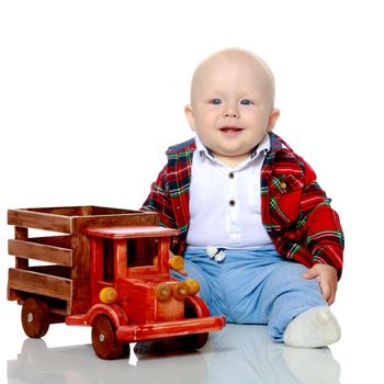 Cute little boy is playing with a toy wooden car on a white background in the studio. The concept of a happy childhood, learning and education in the family. Isolated.
