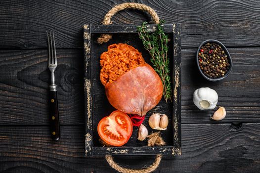 Mallorcan Sobrassada cured pork meat sausage in a wooden tray. Black wooden background. Top view.