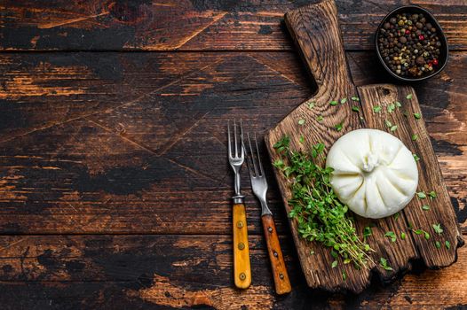 Italian fresh cheese Burrata on a wooden cutting board. Dark wooden background. Top view. Copy space.