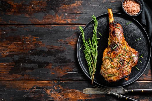 Baked lamb, sheep leg with rosemary. Dark wooden background. Top view. Copy space.