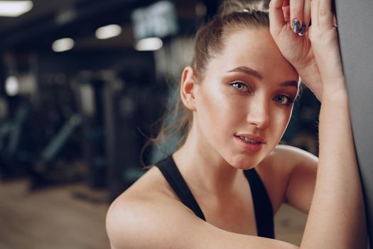 Brunette young woman sitting tired in a gym after workout close up