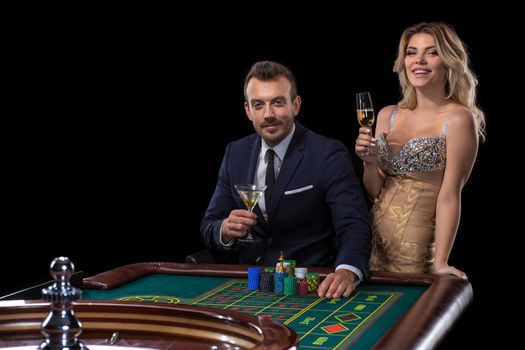 Couple gambling at roulette table in casino. Black background. Excitement. Risk. Luck