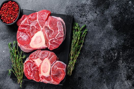 Raw beef meat osso buco shank steak, italian ossobuco. Black background. Top view. Copy space.