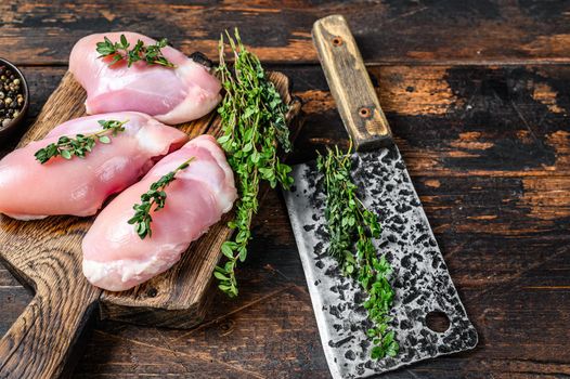 Raw Chicken skinless thigh fillet on a wooden cutting board. Black background. Top view. Copy space.