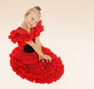 Very sweet little girl sitting on the floor in a bright red dress.the concept of fashion.