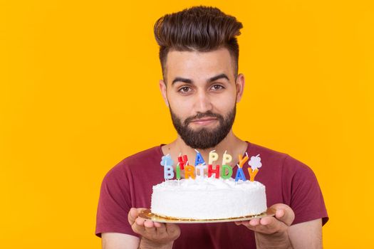 Unidentified young male hipster with a beard holding a cake with the inscription happy birthday congratulations on the anniversary and the holiday. Concept of promotions and discounts