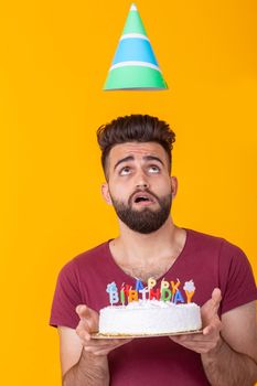 Unidentified young male hipster with a beard holding a cake with the inscription happy birthday congratulations on the anniversary and the holiday. Concept of promotions and discounts