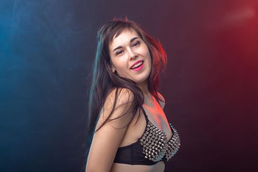 Attractive young sexy brunette woman in riveted top posing in the studio on a dark background. Concept of well-groomed young woman