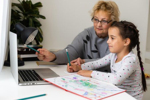 Helpful granny. Helpful loving granny assisting her cute granddaughter making homework