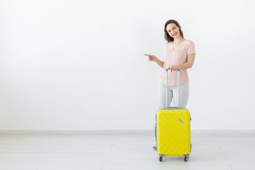 Trip, travel and holidays concept - woman with her yellow suitcase point on copy space.