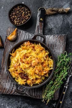 Stewed cabbage Bigos with mushrooms and sausages. Black background. Top view.