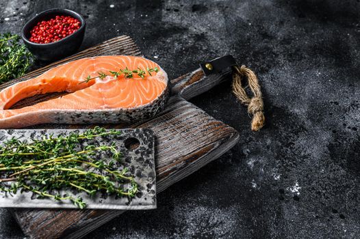 Uncooked salmon sliced in the form of a steak with pepper. Black background. Top view. Copy space.