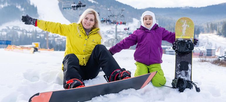 mother and daughter with snowboards in a mountain resort