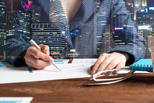 Investment manager analyze financial diagram at wooden desk. Close up woman hand with pen. Strategy planning and banking. Analyst working at workplace in office. Business accounting and management.