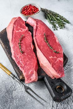 Raw rump or picanha steak on a wooden cutting board. White background. Top view.