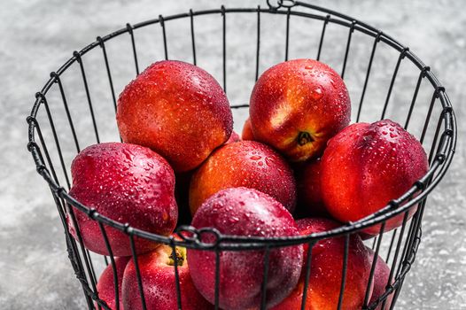 Ripe red nectarines in a basket. Gray background. Top view.