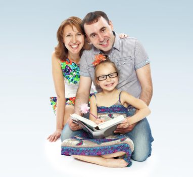 Family of three mom dad and daughter reading a book.