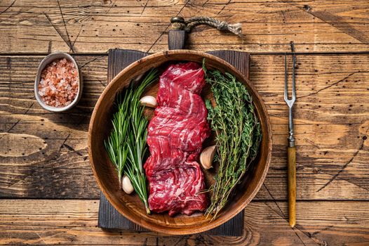 Prime Raw machete skirt beef steak in woode plate with herbs. wooden background. Top view.