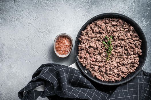 Fried mince beef and lamb meat in a pan with herbs. White background. Top view. Copy space.