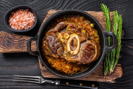 Stew veal shank meat OssoBuco, italian osso buco steak. Black wooden background. Top view.