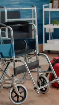 Empty nursing home room with wheelchair and medical equipment for retired and disabled people. Nobody in space with bag and transportation object for healthcare and wellness at facility.