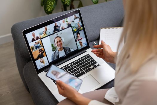 Back view of business woman talking to her colleagues about plan in video conference. Multiethnic business team using laptop for a online meeting in video call. Group of people smart working from home