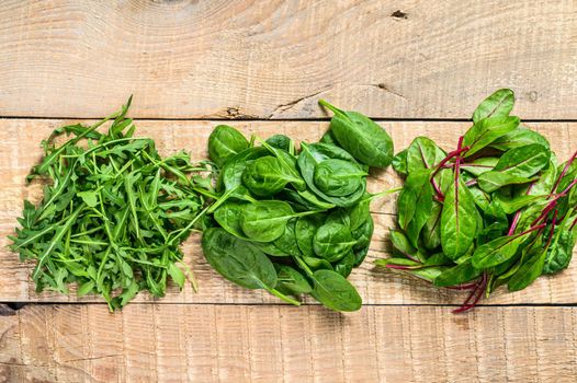 Mix Salad leafs, Arugula, Spinach and swiis Chard. Wooden background. Top view.