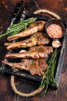 Grilled lamb chops steaks in a wooden tray. Dark background. Top view.