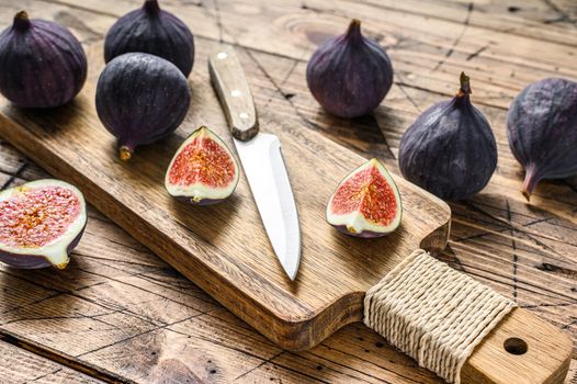 Sliced purple figs on a cutting Board. Wooden background. Top view