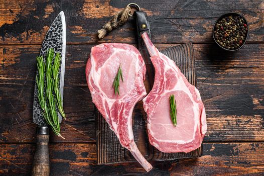 Marbled raw pork chops meat steak or tomahawk. Dark wooden background. Top view.