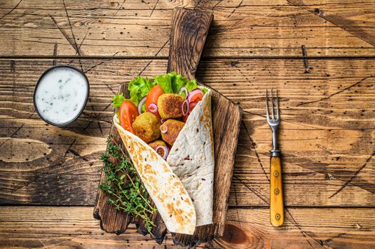 Vegetarian Tortilla wrap with falafel and fresh salad, vegan tacos. wooden background. Top view.