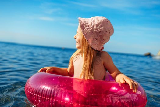 Girl kid in pink panama swimming in sea with pink circle