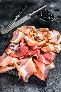 Set of cold cured italian meat Ham, prosciutto, pancetta, bacon. Black background. Top view.