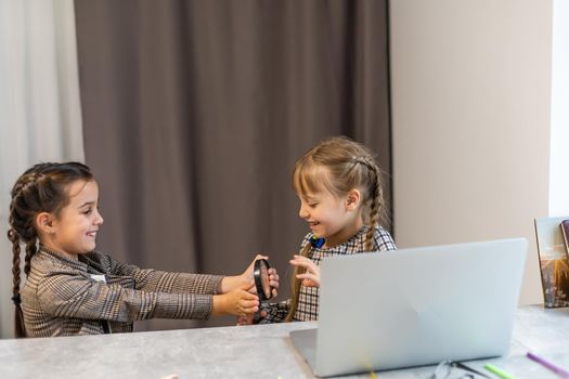 Education at home concept - two Cute little playful girls studying doing homework on laptop