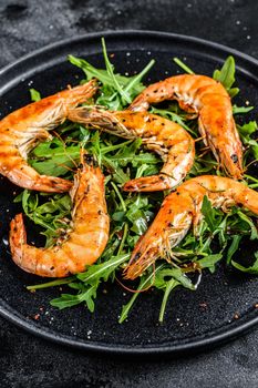 Salad with grilled giant tiger shrimps, prawns and arugula. Black background. Top view.