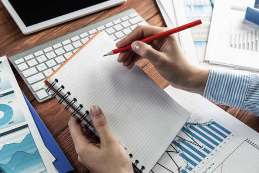 close-up, female hands hold a notebook and pencil. Business woman working at the table in the office