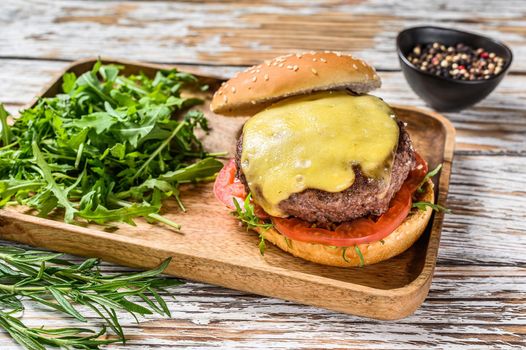 Big cheeseburger with beef, tomato, cheese and arugula. wooden background. Top view.