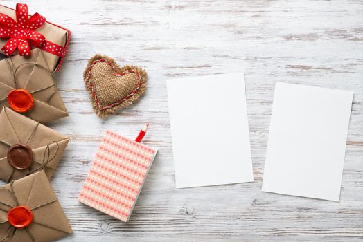 Flat lay cute composition with handmade fabric heart. White paper and retro mail envelopes on wooden table. Happy birthday or anniversary congratulation. Romantic message template with copy space