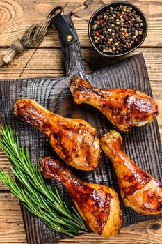 Barbecue roasted chicken drumsticks on a wooden cutting board. wooden background. top view.