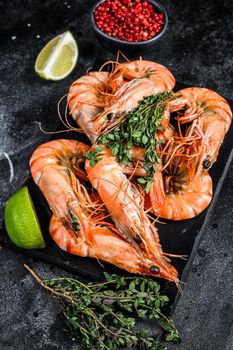 Red Langostino shrimps Prawns on a marble board. Black background. Top view.