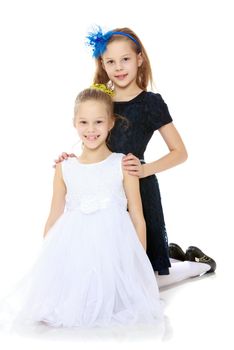 Beautiful little twin girls in holiday dresses posing for the camera.Isolated on white background.