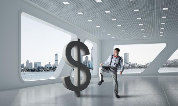 Young furious businessman going to crash with kick stone dollar symbol